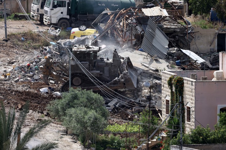 An Israeli army bulldozer operates amid the rubble of a demolished building during a raid in the occupied West Bank town of Deir al-Ghusun near Tulkarem on May 4, 2024. (Photo by JAAFAR ASHTIYEH / AFP)